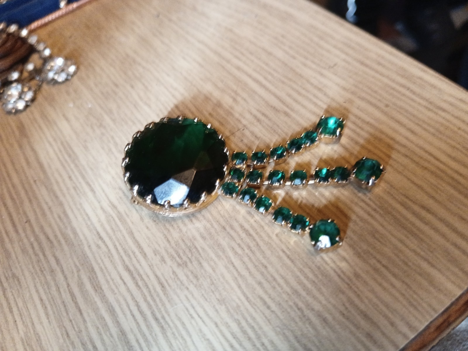 This vintage-style brooch features a large, dark green central rhinestone.