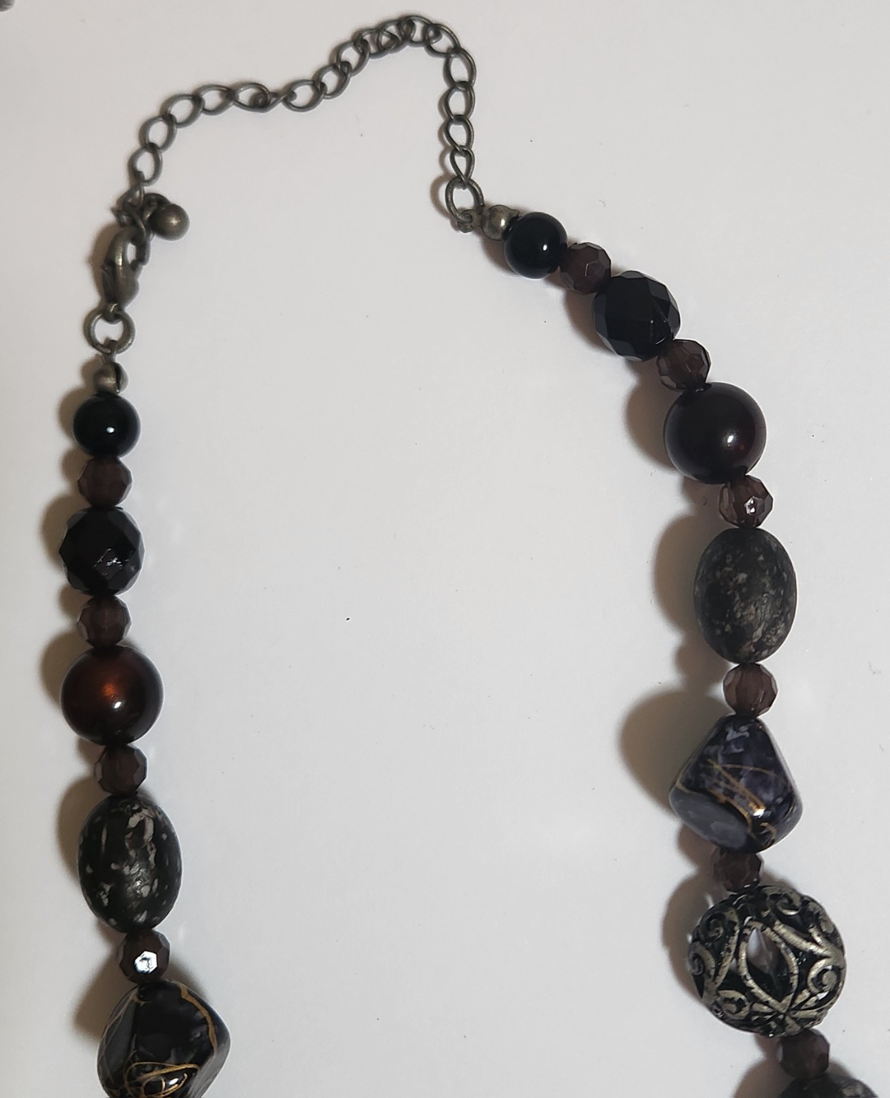 Handmade artisan necklace features chunky, speckled black beads and ornate.