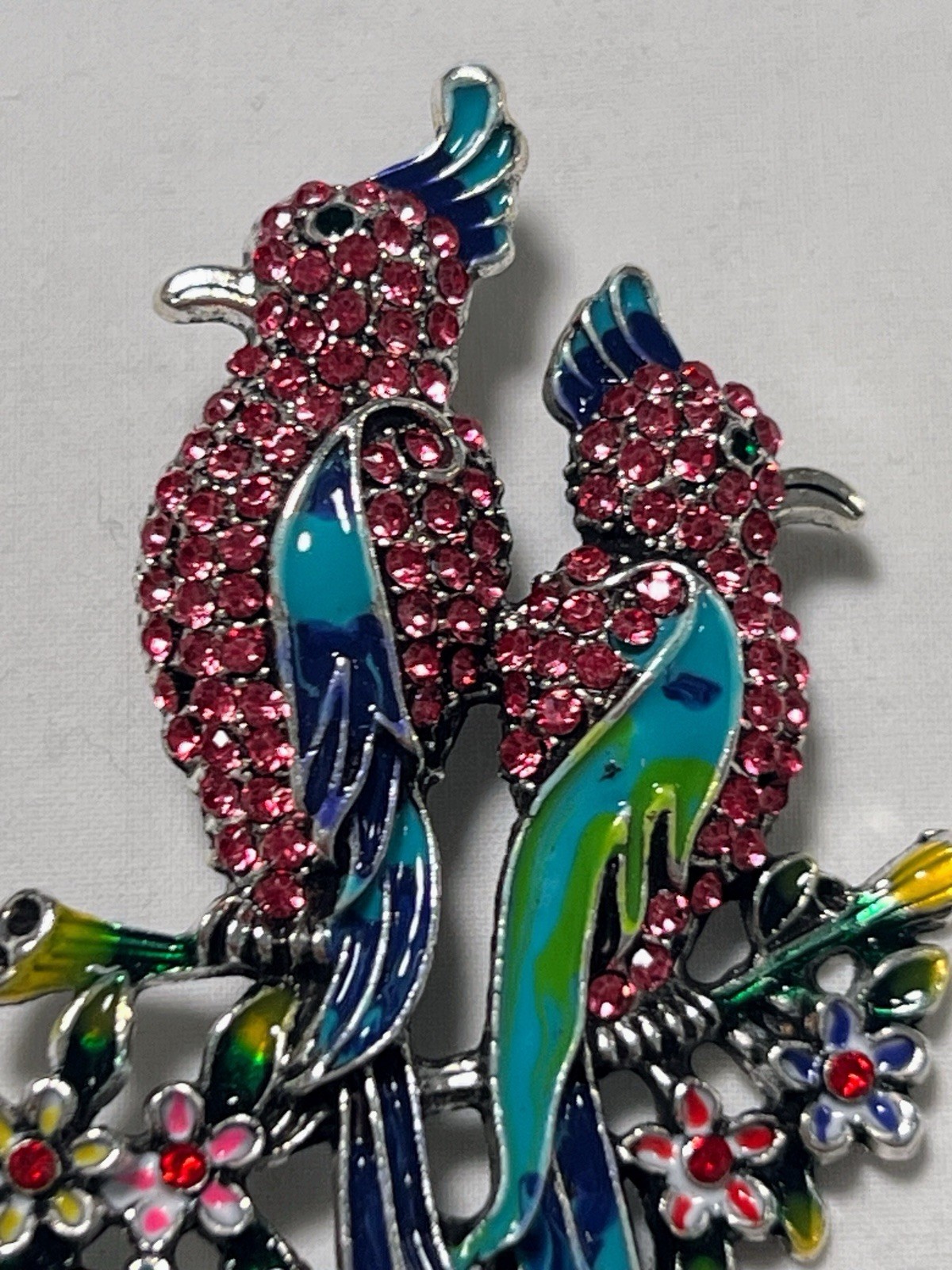 Pink rhinestone green blue enamel Birds of Paradise pin brooch sitting on flower