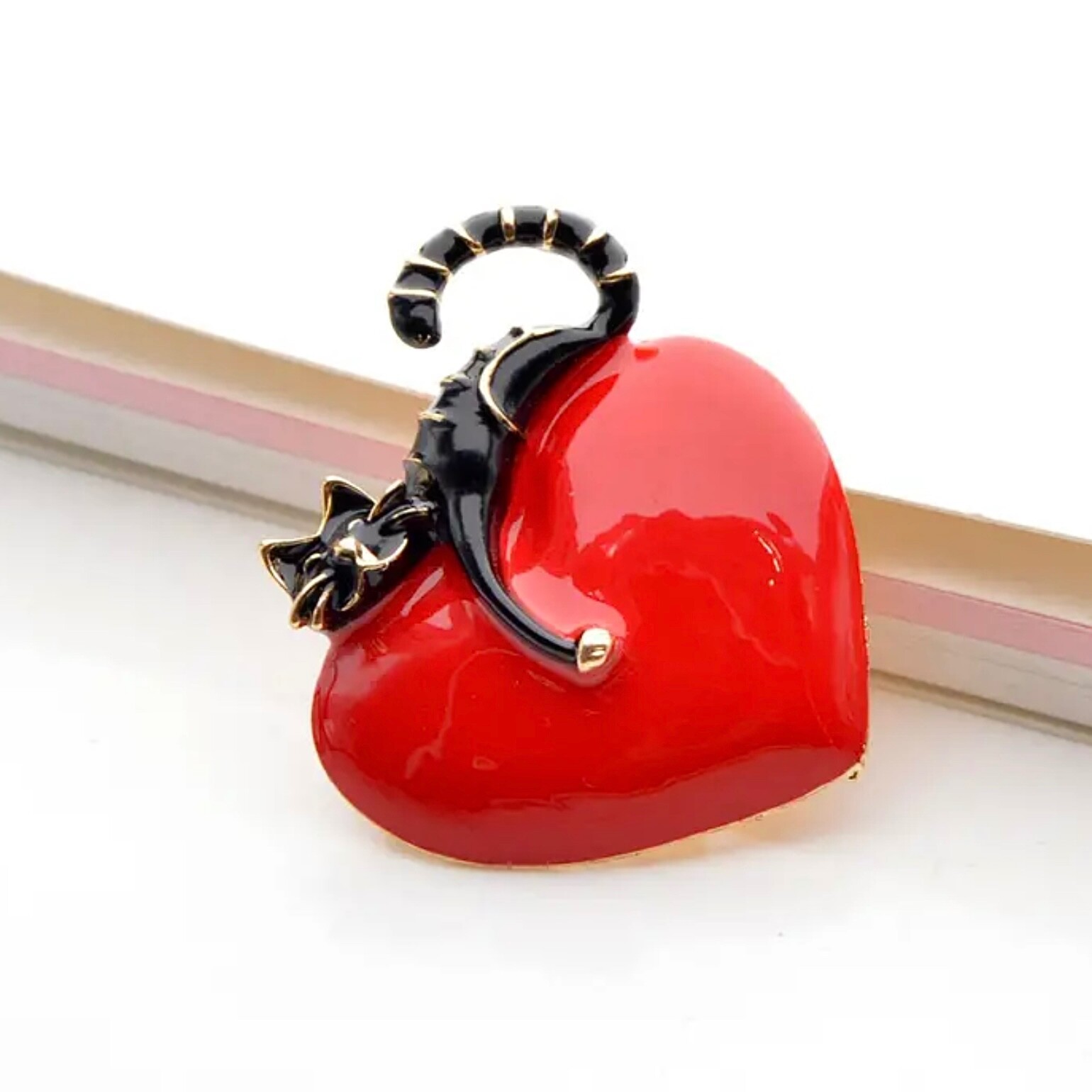 Rich red, shiny heart with comfy cat resting on top. Puffed up. Pin, brooch.