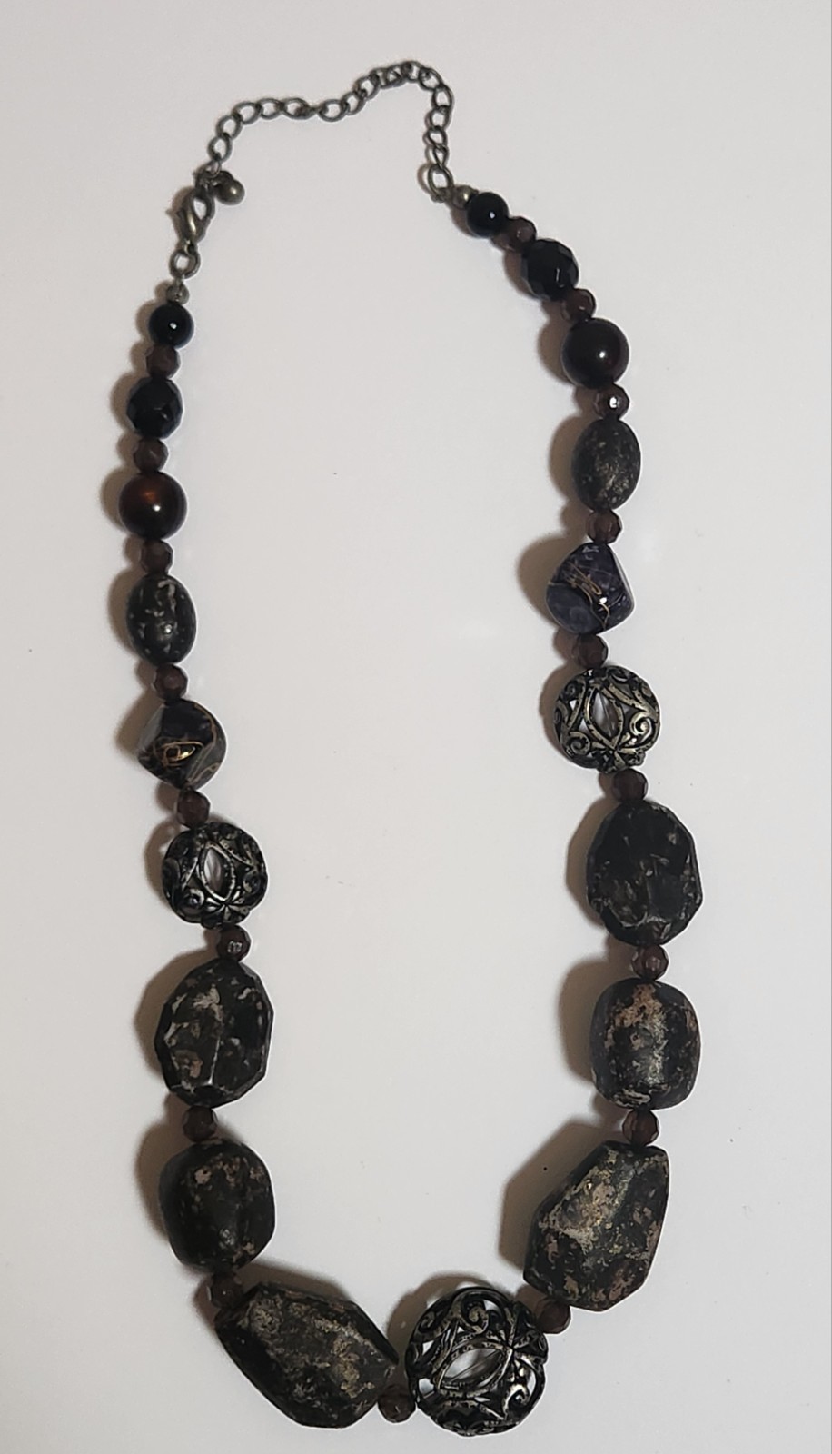 Handmade artisan necklace features chunky, speckled black beads and ornate.