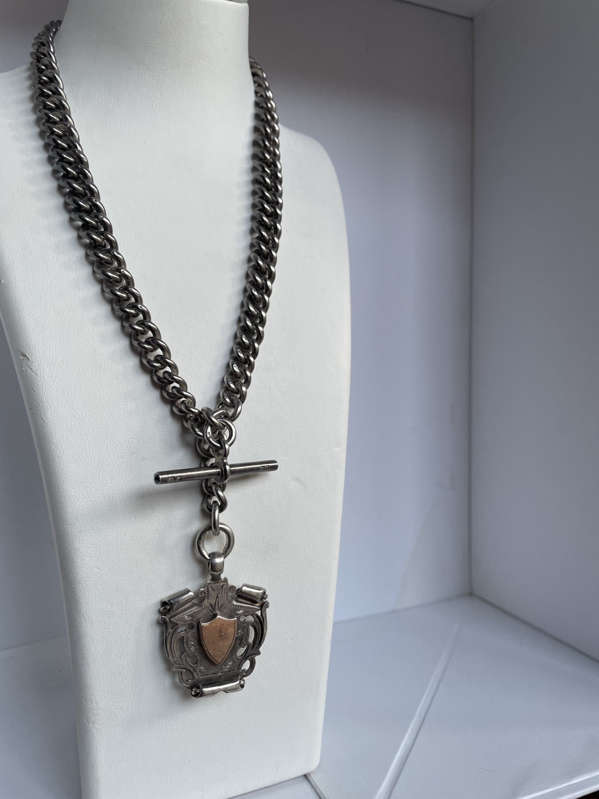 Sterling silver stamped antique fob chain w’ T bar + shield. 84 grs. L 38.5 cms