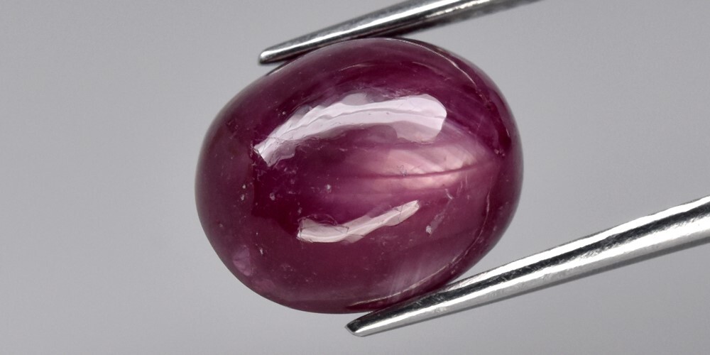 9.05ct 12×9.8mm Oval Cab Purplish Red 6 Ray Star Ruby (Heated Glass Filling)