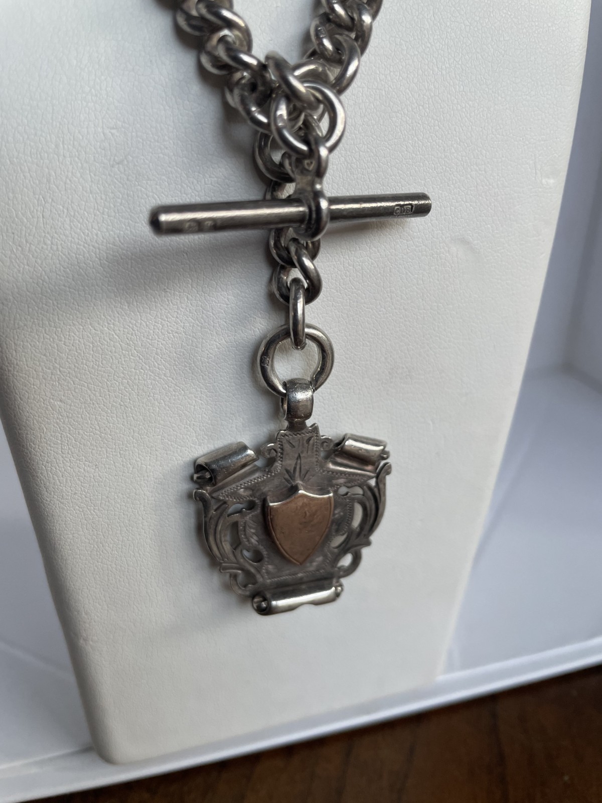Sterling silver stamped antique fob chain w’ T bar + shield. 84 grs. L 38.5 cms