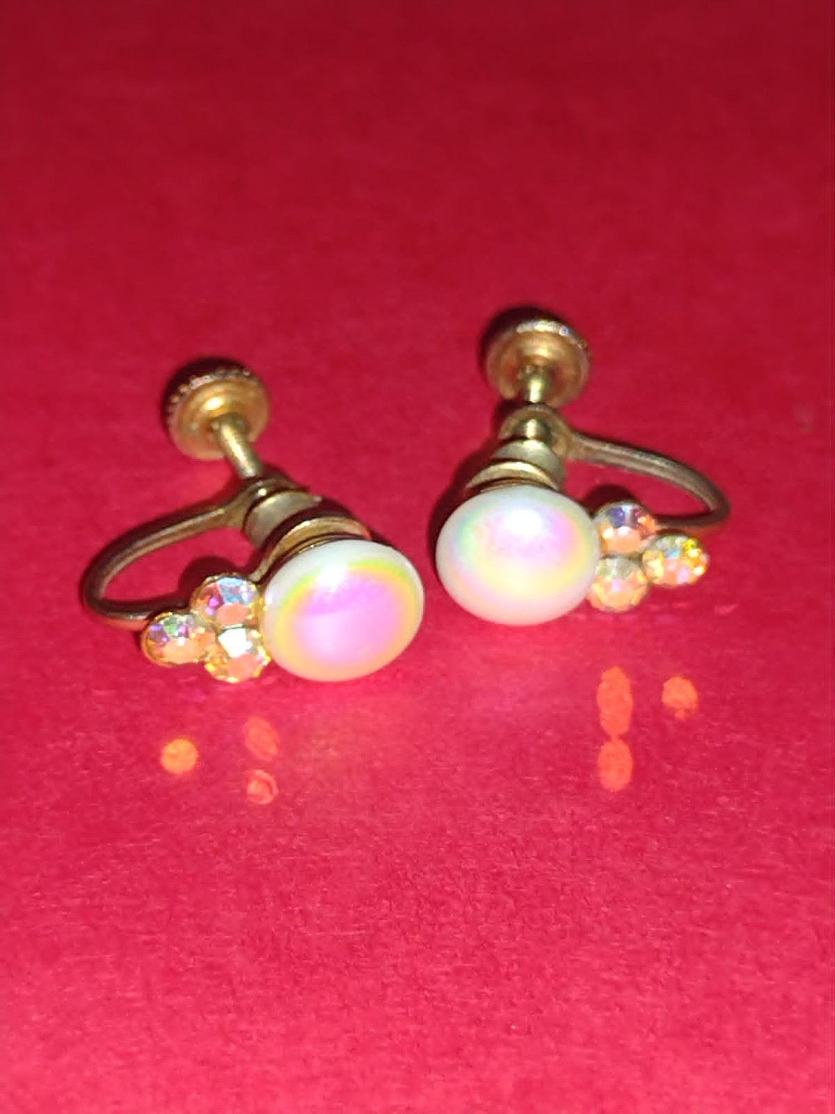 Screw-on gold-tone earrings with a whhite stone in the center and multicolor gem