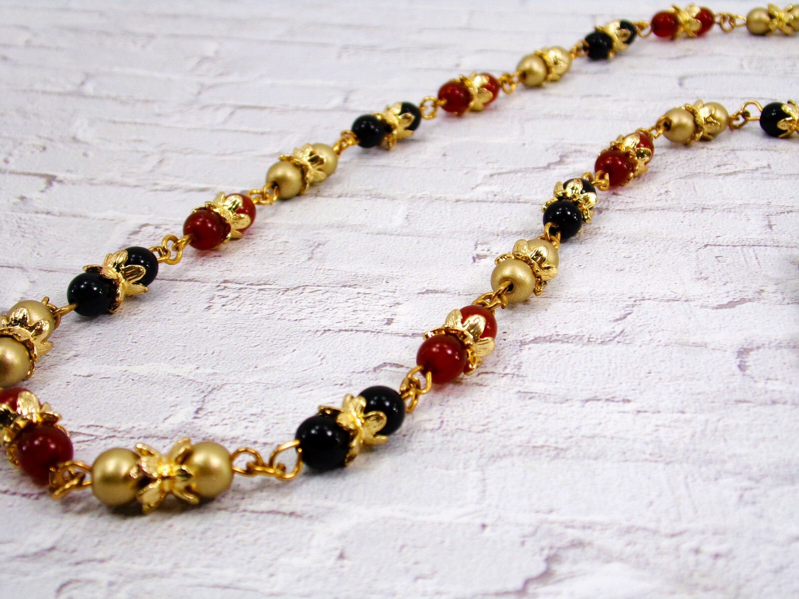 Multi color glass bead necklace with a mix of red, black, and gold colors New