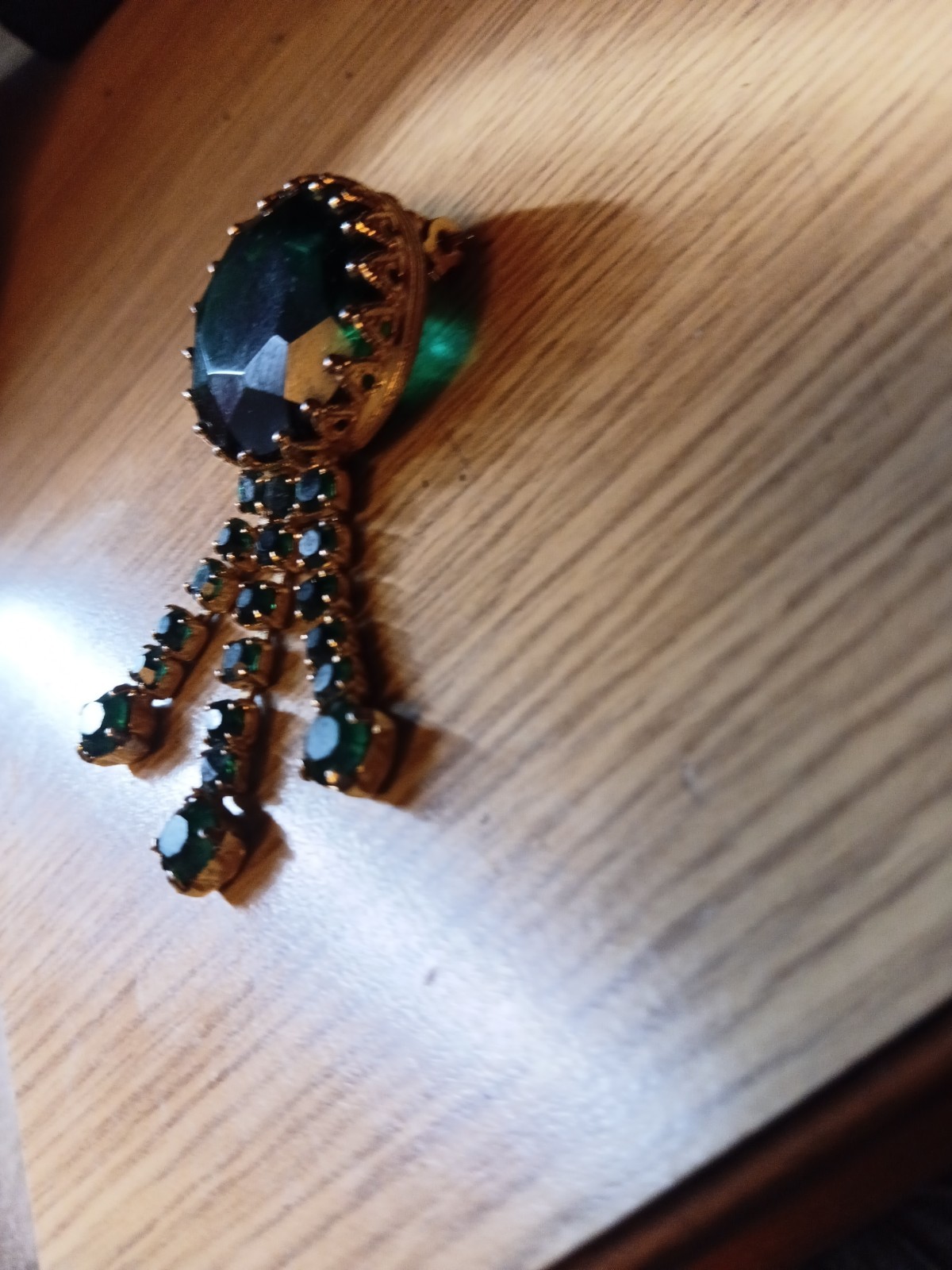 This vintage-style brooch features a large, dark green central rhinestone.