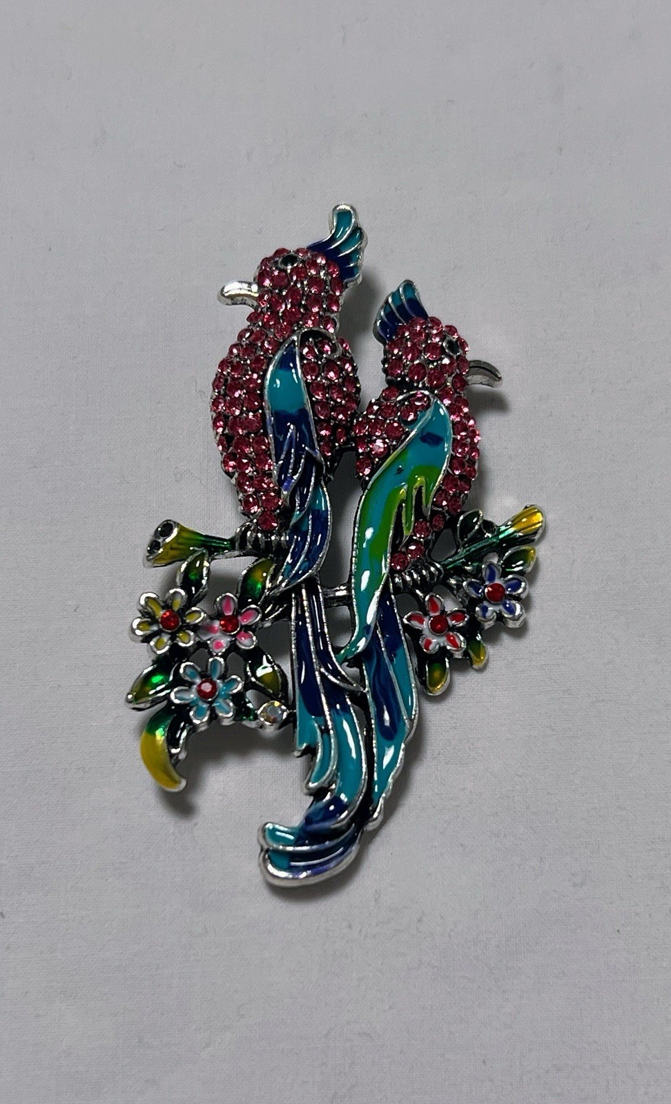 Pink rhinestone green blue enamel Birds of Paradise pin brooch sitting on flower