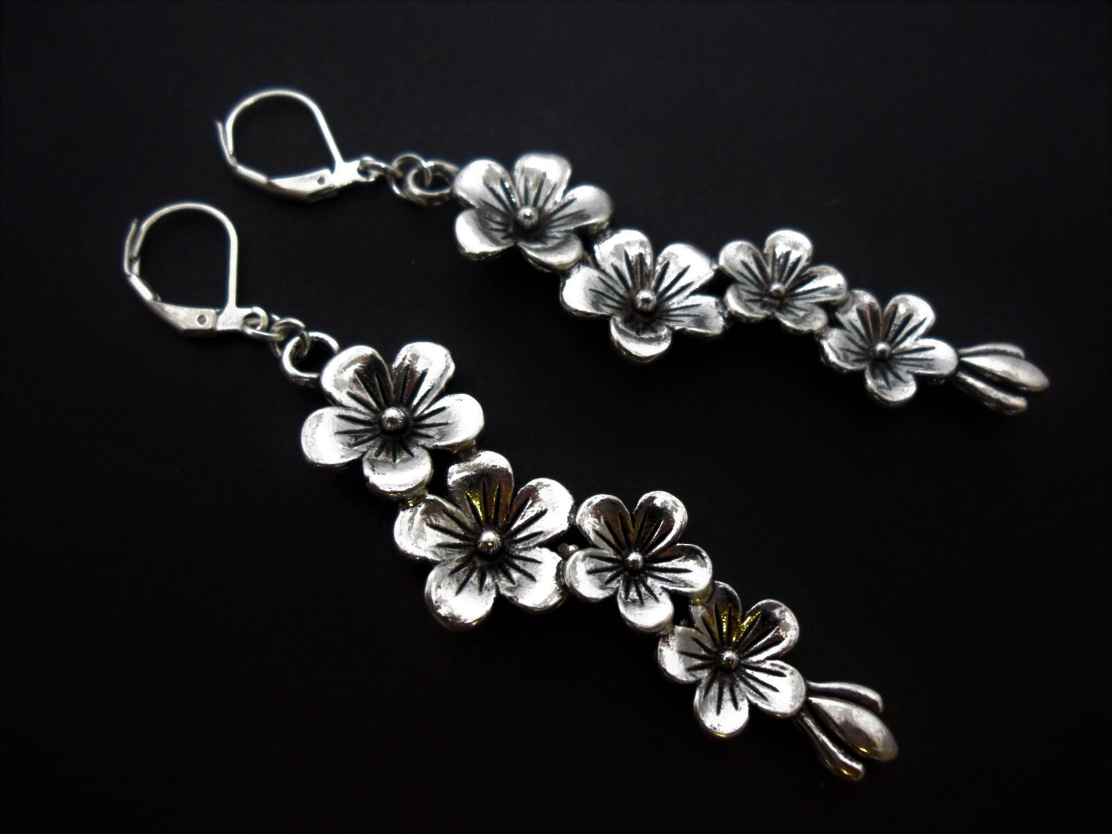 A PAIR OF TIBETAN SILVER DANGLY FLOWER THEMED LEVERBACK HOOK EARRINGS.