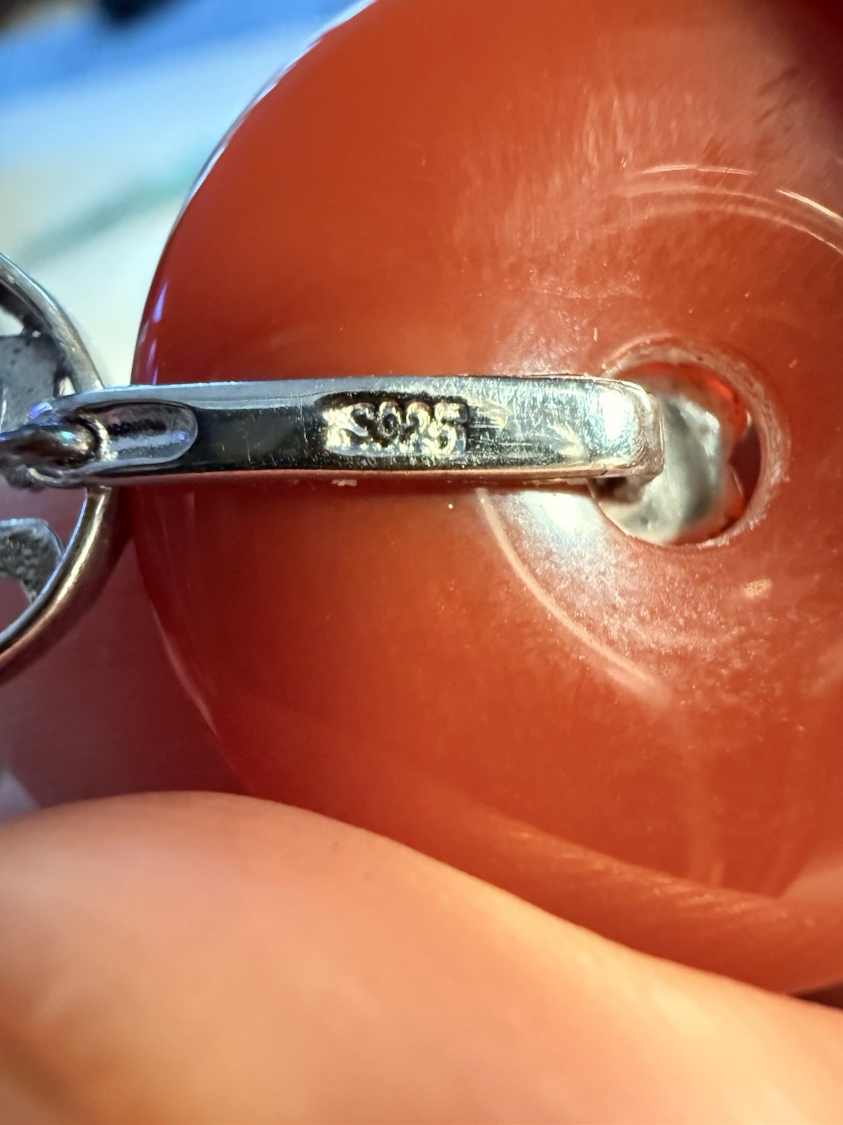Pendant featuring a sterling silver bail with a red, circular stone attached
