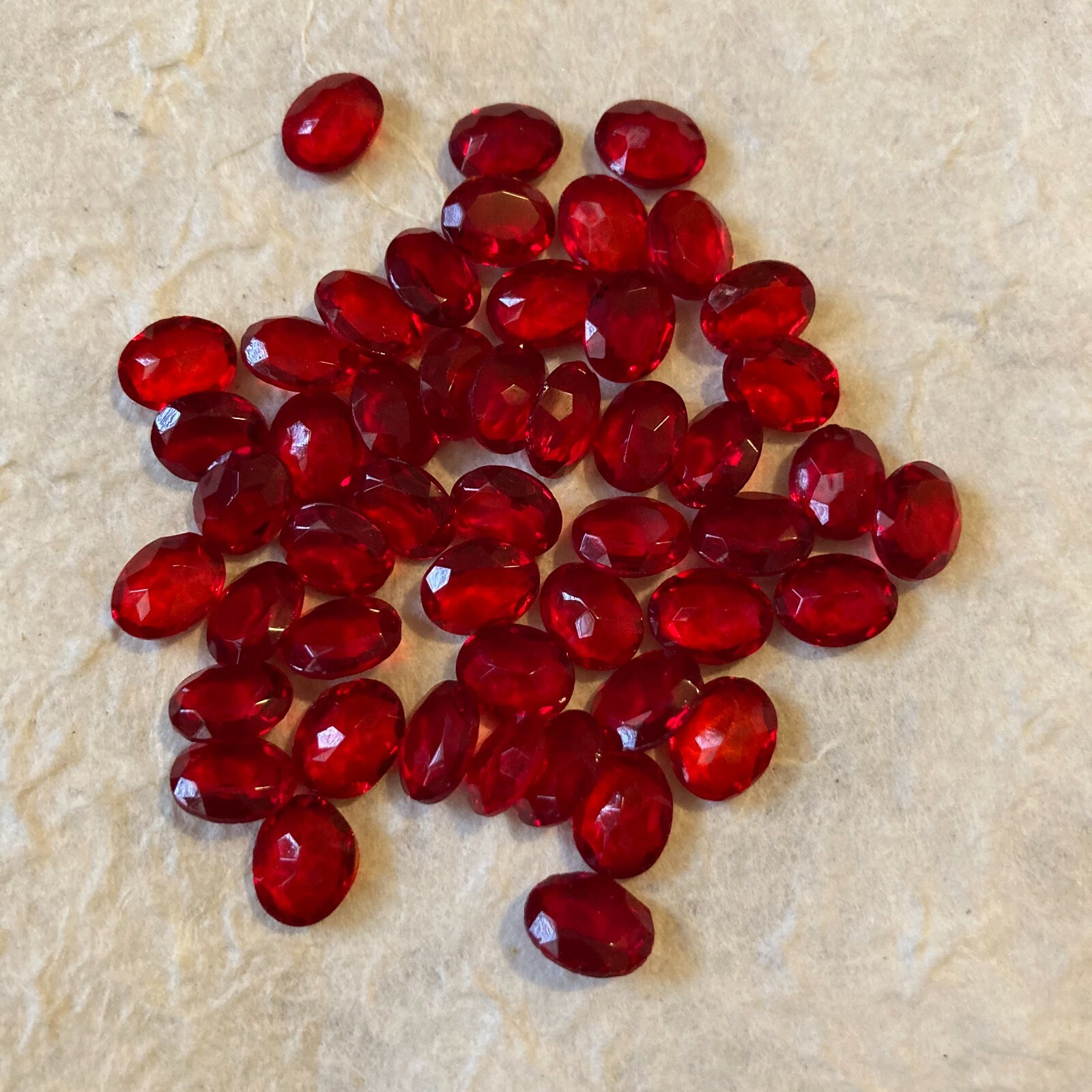 AB140 9x7mm siam oval faceted glass jewels, unfoiled pointed back (48)