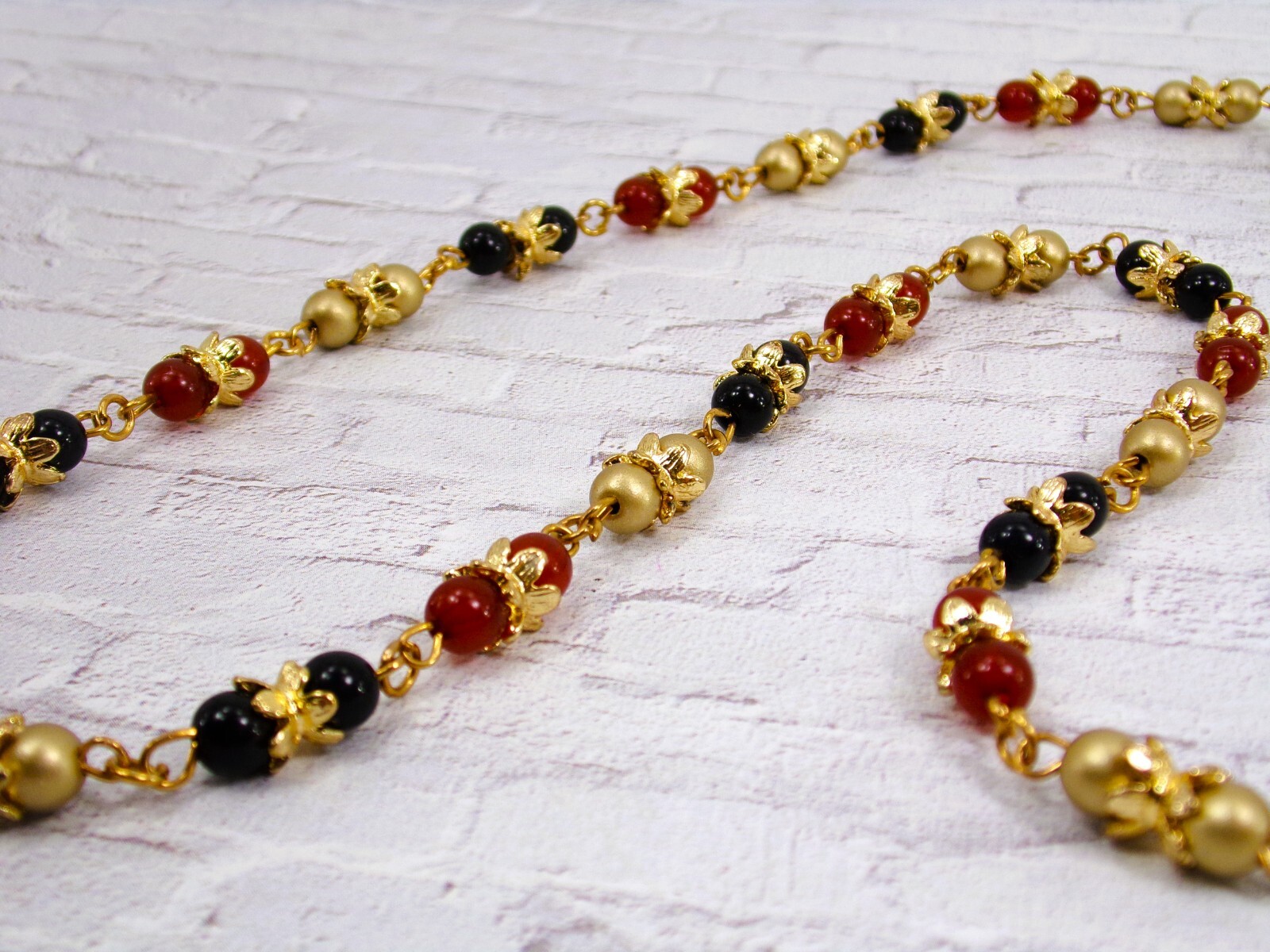 Multi color glass bead necklace with a mix of red, black, and gold colors New