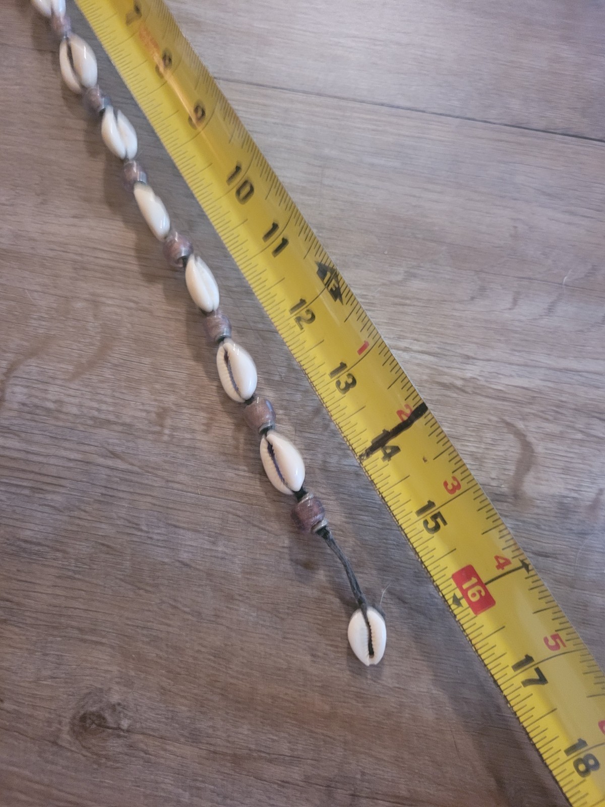 boho-style cowrie shell choker necklace featuring purple beads on a cord.