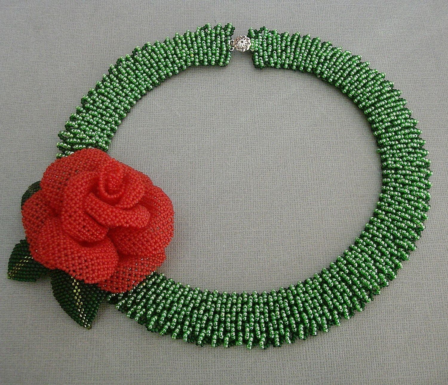 Handmade green beaded necklace with red rose centerpiece.