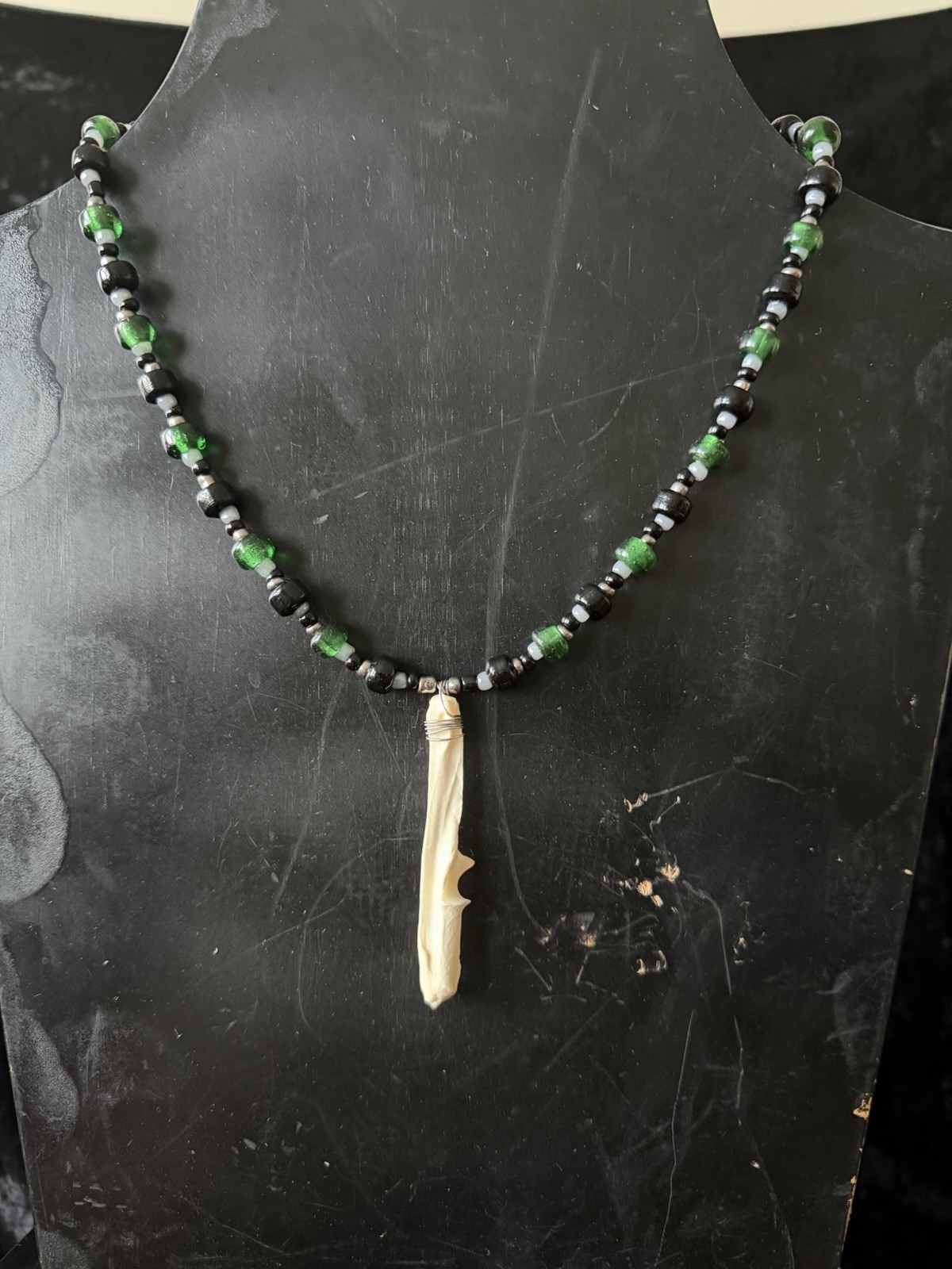 Armadillo leg bone necklace with green, black, gray, and silver glass beads
