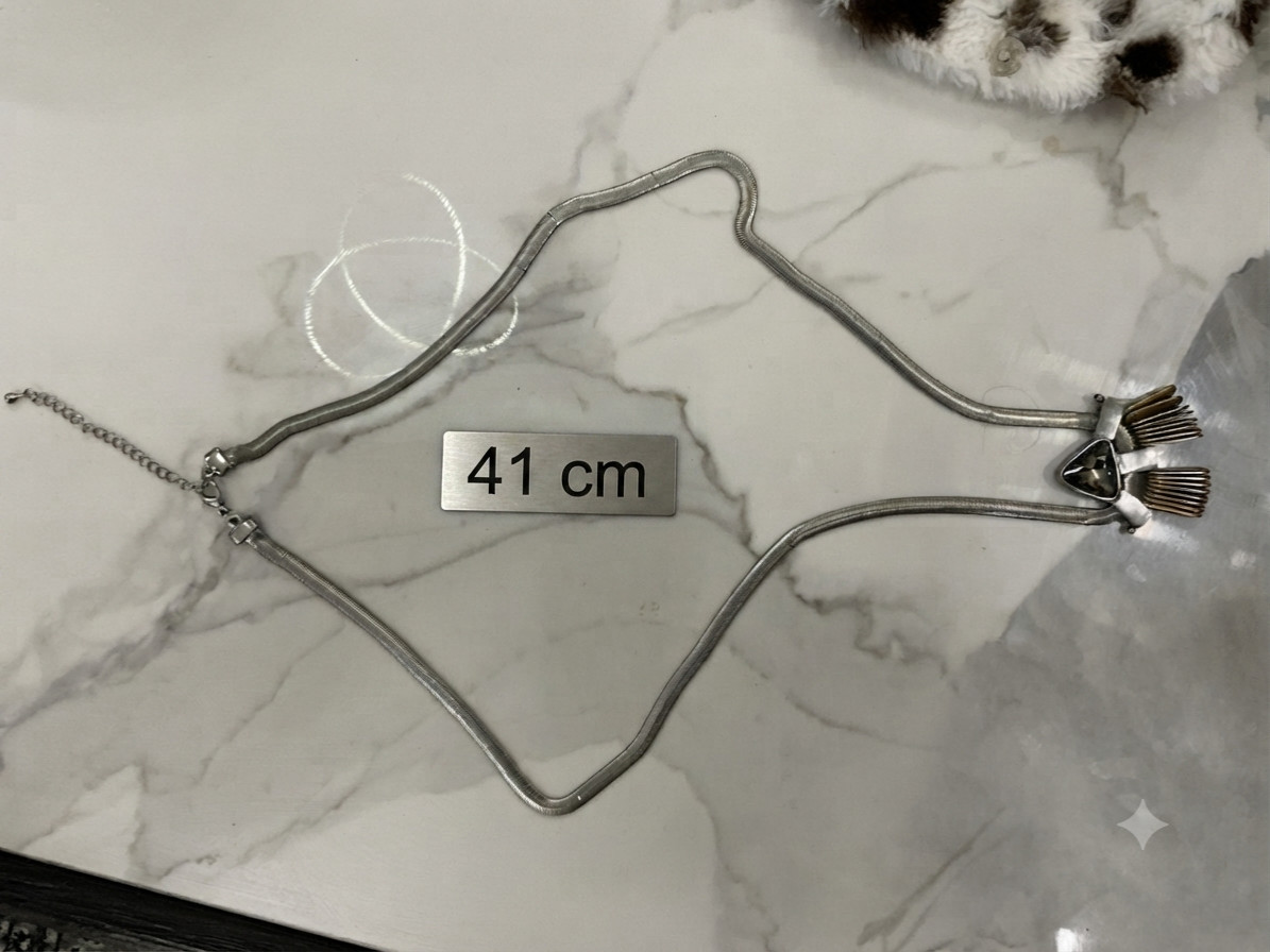 This piece features a flat silver snake chain and a prominent geometric pendant.