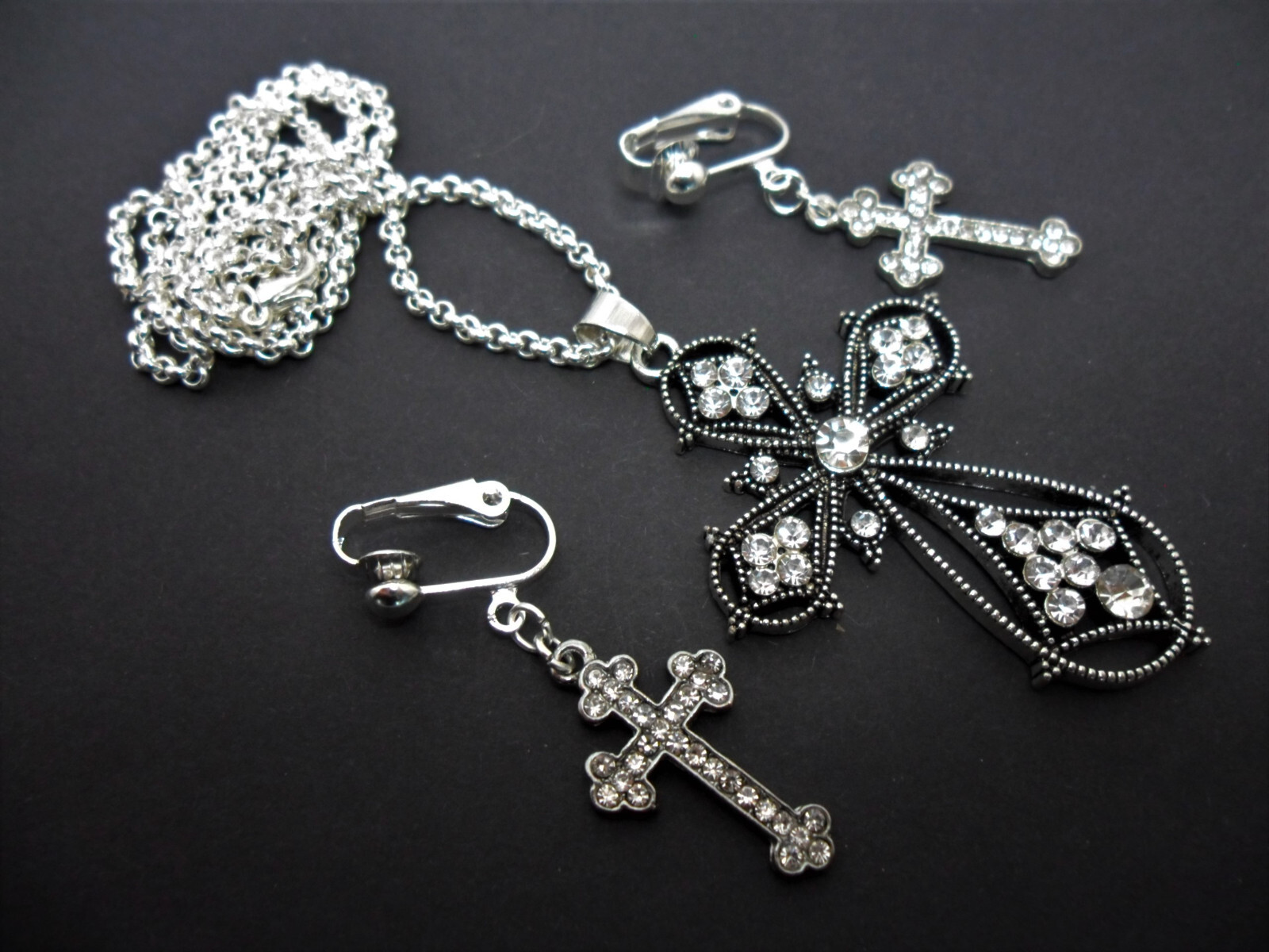 A SILVER & CLEAR CRYSTAL/DIAMANTE CROSS NECKLACE AND CLIP ON EARRING SET. NEW.