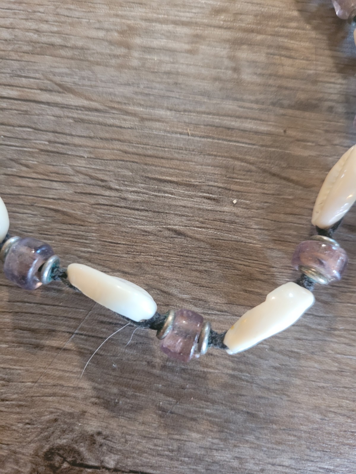 boho-style cowrie shell choker necklace featuring purple beads on a cord.
