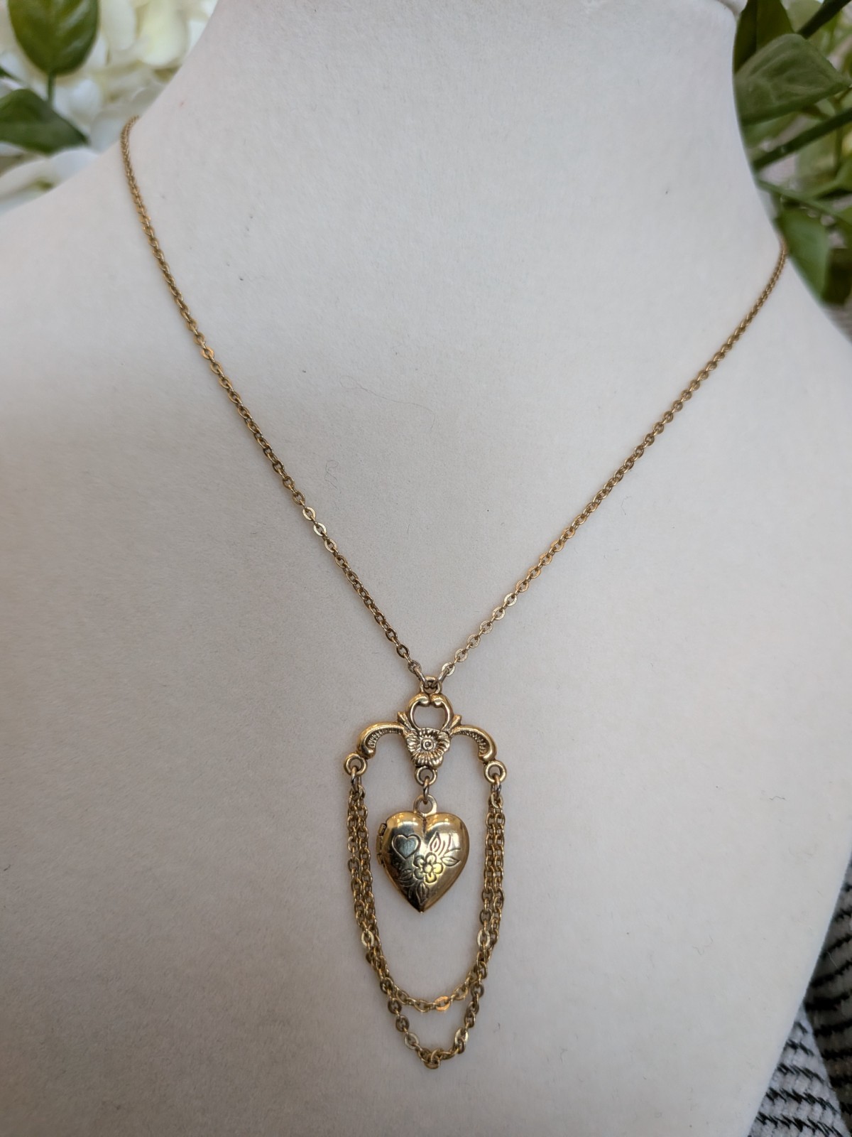 1928 necklace features a gold-tone chain and a delicate heart locket